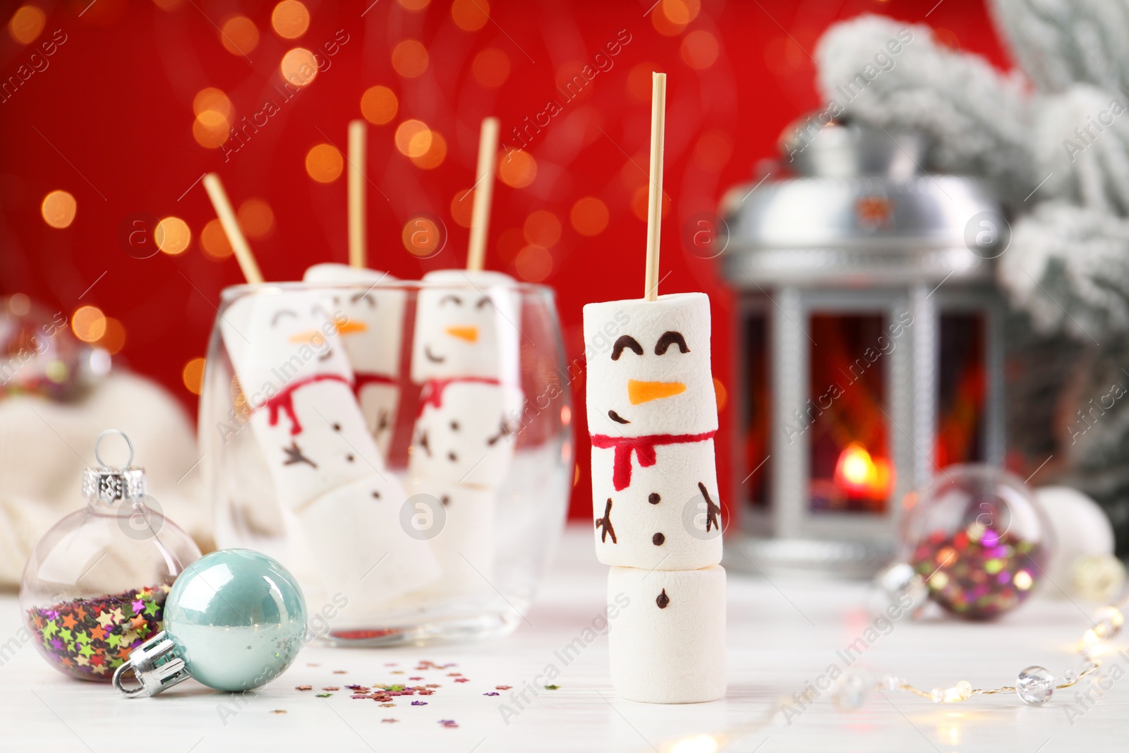 Photo of Funny snowmen made with marshmallows and Christmas decor on white table, selective focus