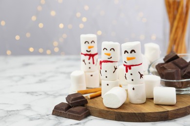 Photo of Funny snowmen made with marshmallows on white marble table. Space for text