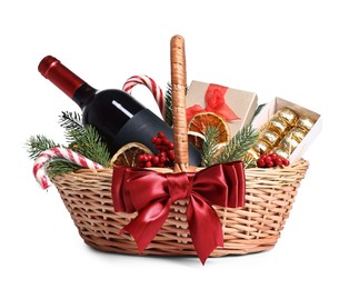 Photo of Wicker gift basket with wine and Christmas decor isolated on white