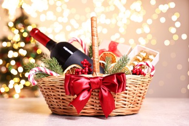 Wicker gift basket with wine and Christmas decor on light textured table