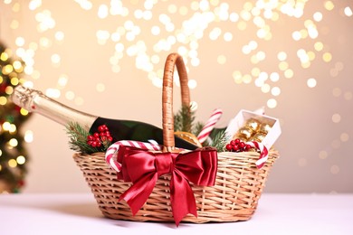 Wicker gift basket with sparkling wine and Christmas decor on white table