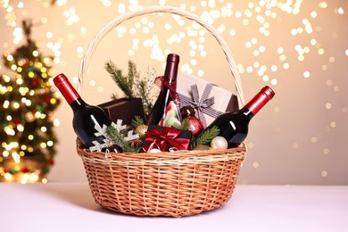 Photo of Wicker gift basket with wine and Christmas decor on white table