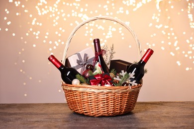 Wicker gift basket with wine and Christmas decor on grey textured table