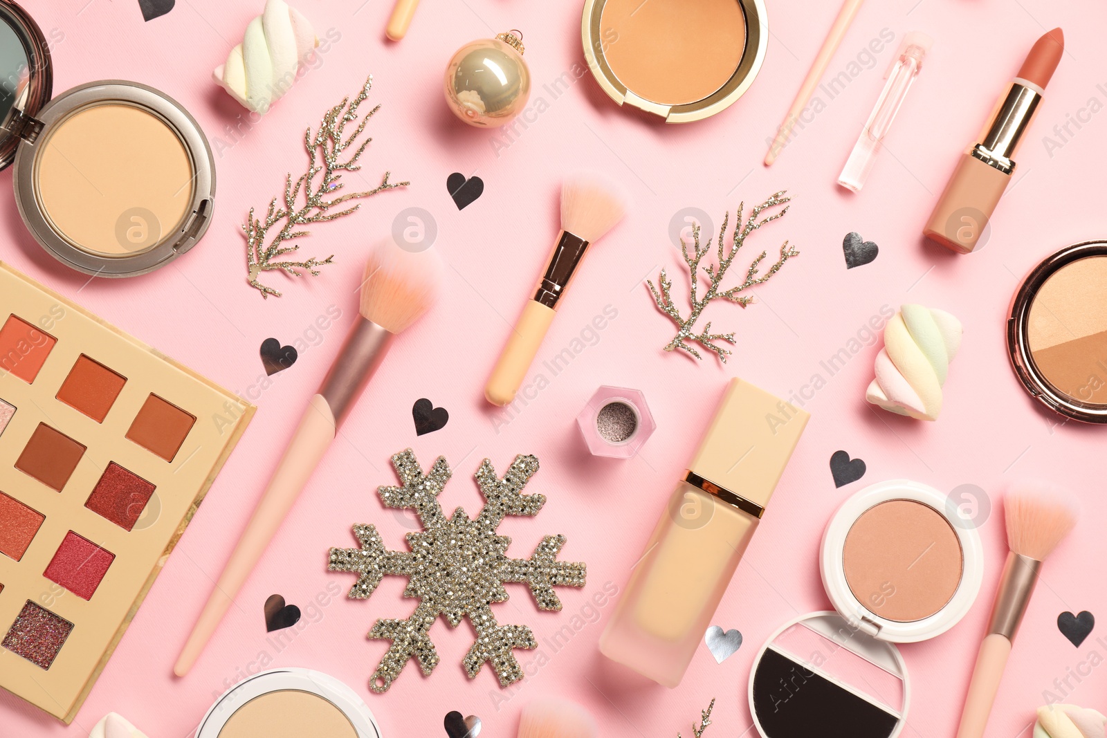 Photo of Different makeup brushes, decorative cosmetics and Christmas decor on pink background, flat lay