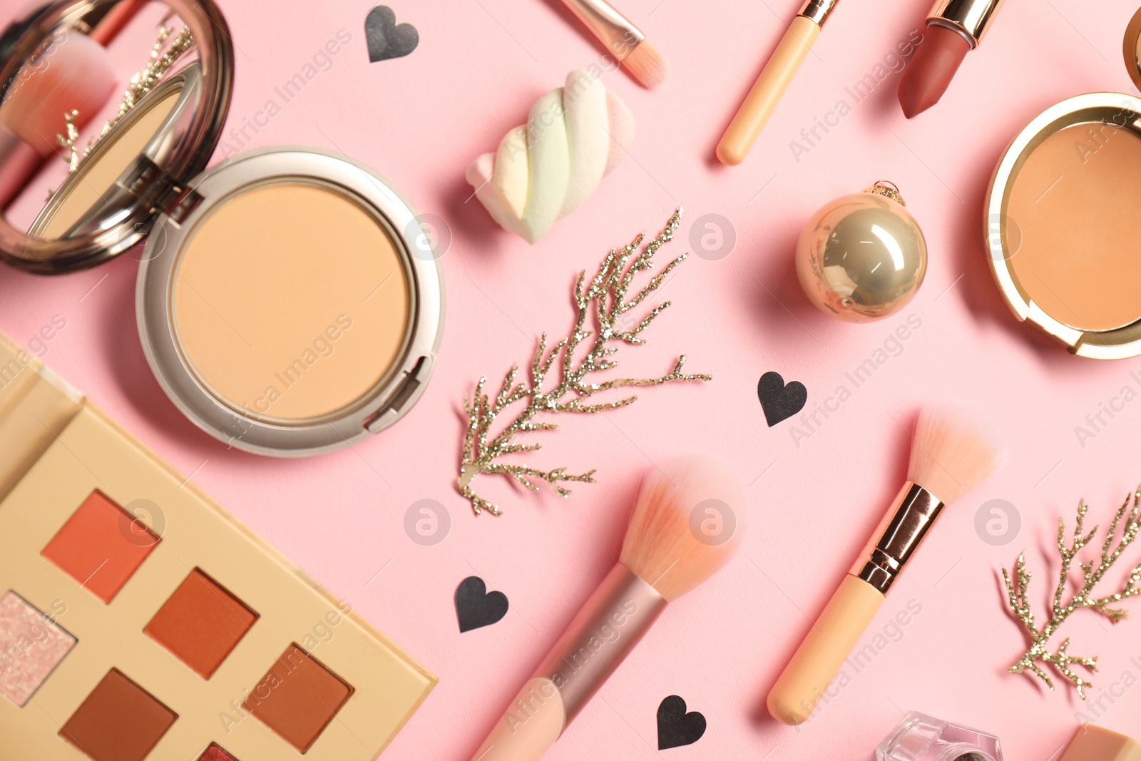 Photo of Different makeup brushes, decorative cosmetics and Christmas decor on pink background, flat lay