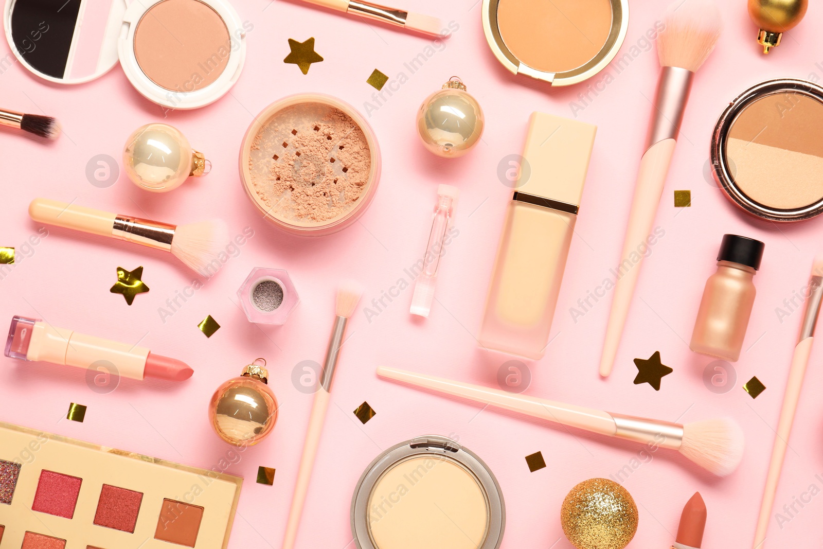 Photo of Different makeup brushes, decorative cosmetics and Christmas decor on pink background, flat lay