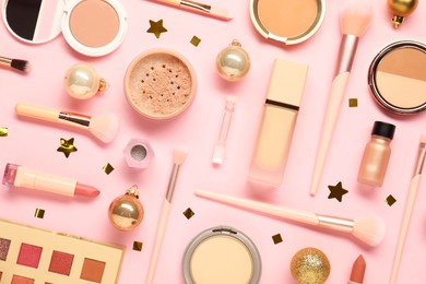 Photo of Different makeup brushes, decorative cosmetics and Christmas decor on pink background, flat lay