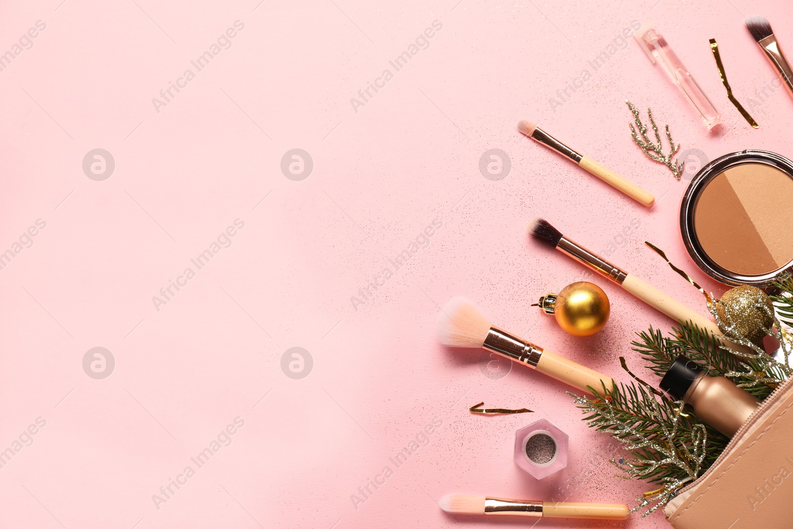 Photo of Different makeup brushes, decorative cosmetics and Christmas decor on pink background, flat lay. Space for text