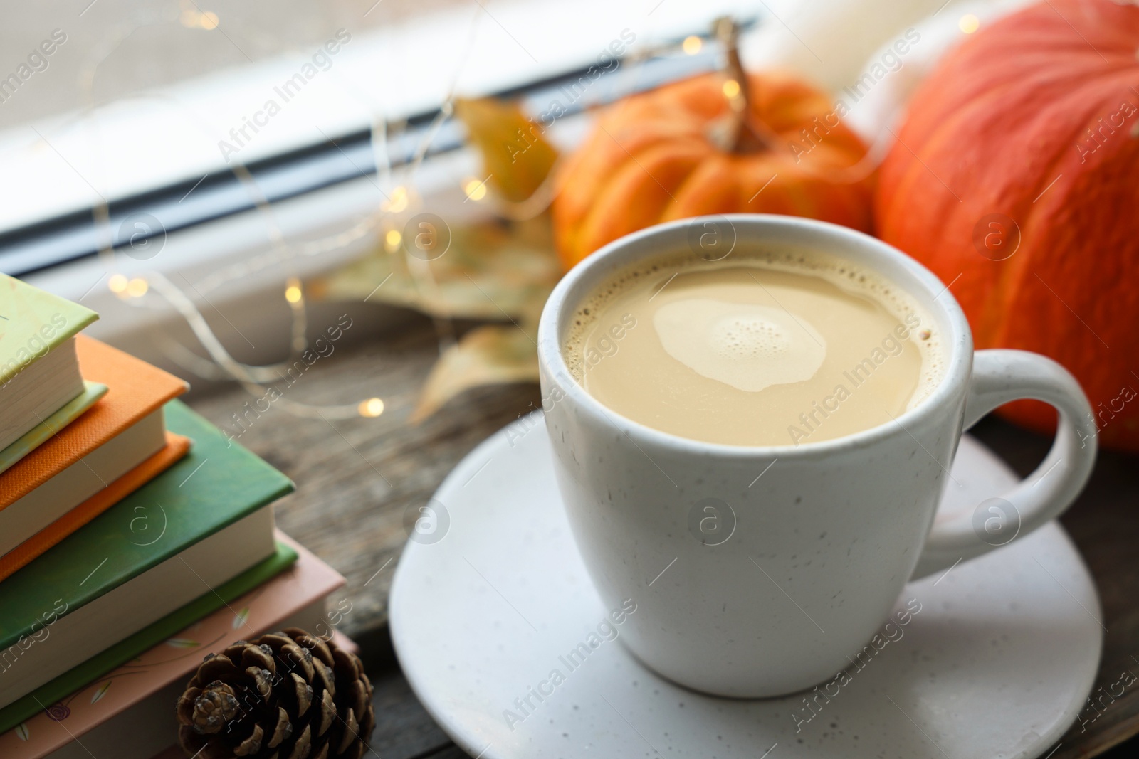 Photo of Cup of coffee, books and autumn decor on wooden table, closeup