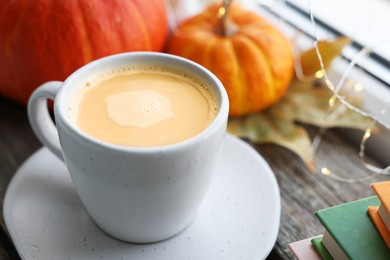 Cup of coffee and pumpkins on wooden table, closeup. Autumn atmosphere