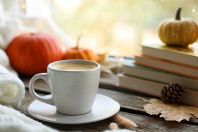 Cup of coffee, books and autumn decor on wooden table, closeup