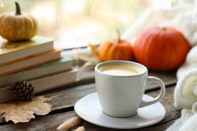 Cup of coffee, books and autumn decor on wooden table, closeup