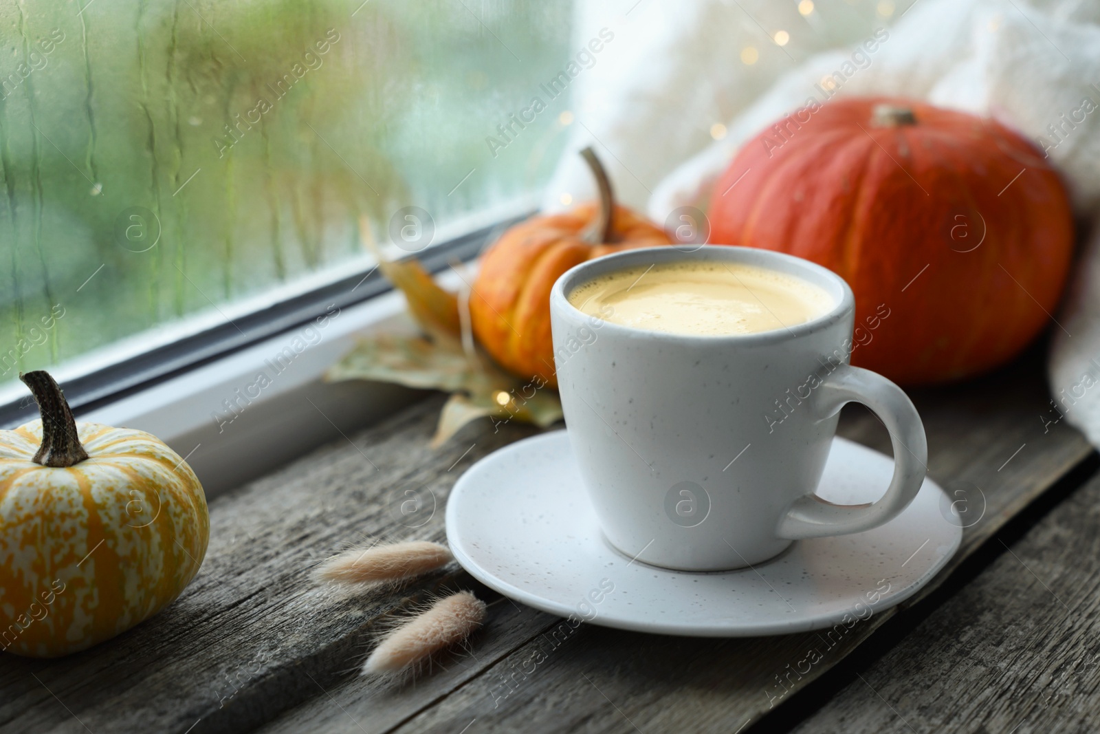 Photo of Cup of coffee and autumn decor on window sill, closeup