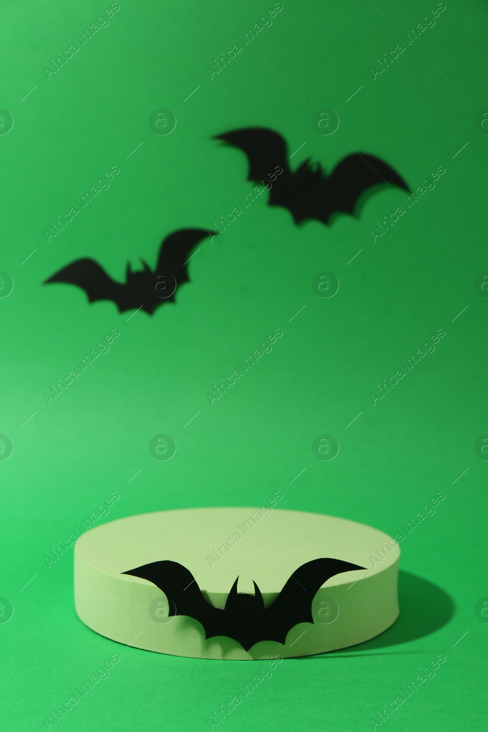 Photo of Halloween celebration. Podium and paper bats on green background, space for text