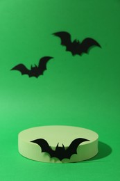 Photo of Halloween celebration. Podium and paper bats on green background, space for text