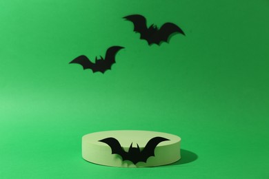 Halloween celebration. Podium and paper bats on green background, space for text