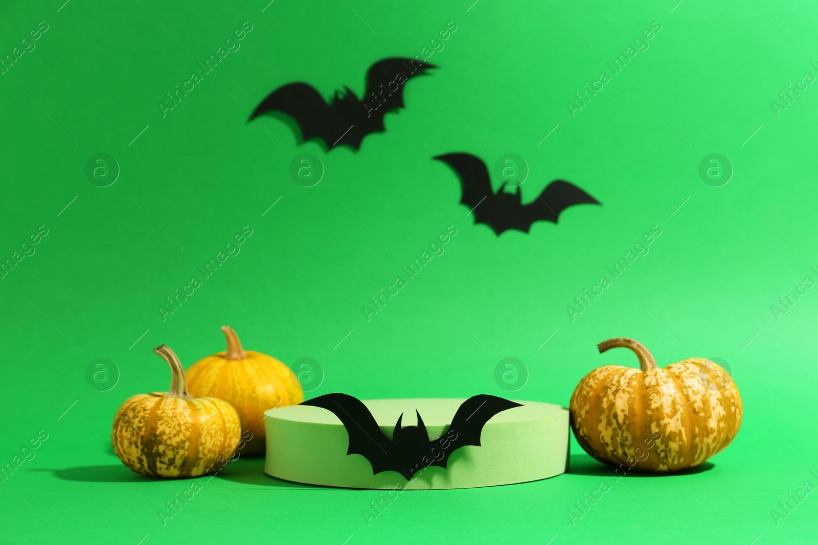 Photo of Presentation of product. Podium and Halloween decor on green background. Space for text