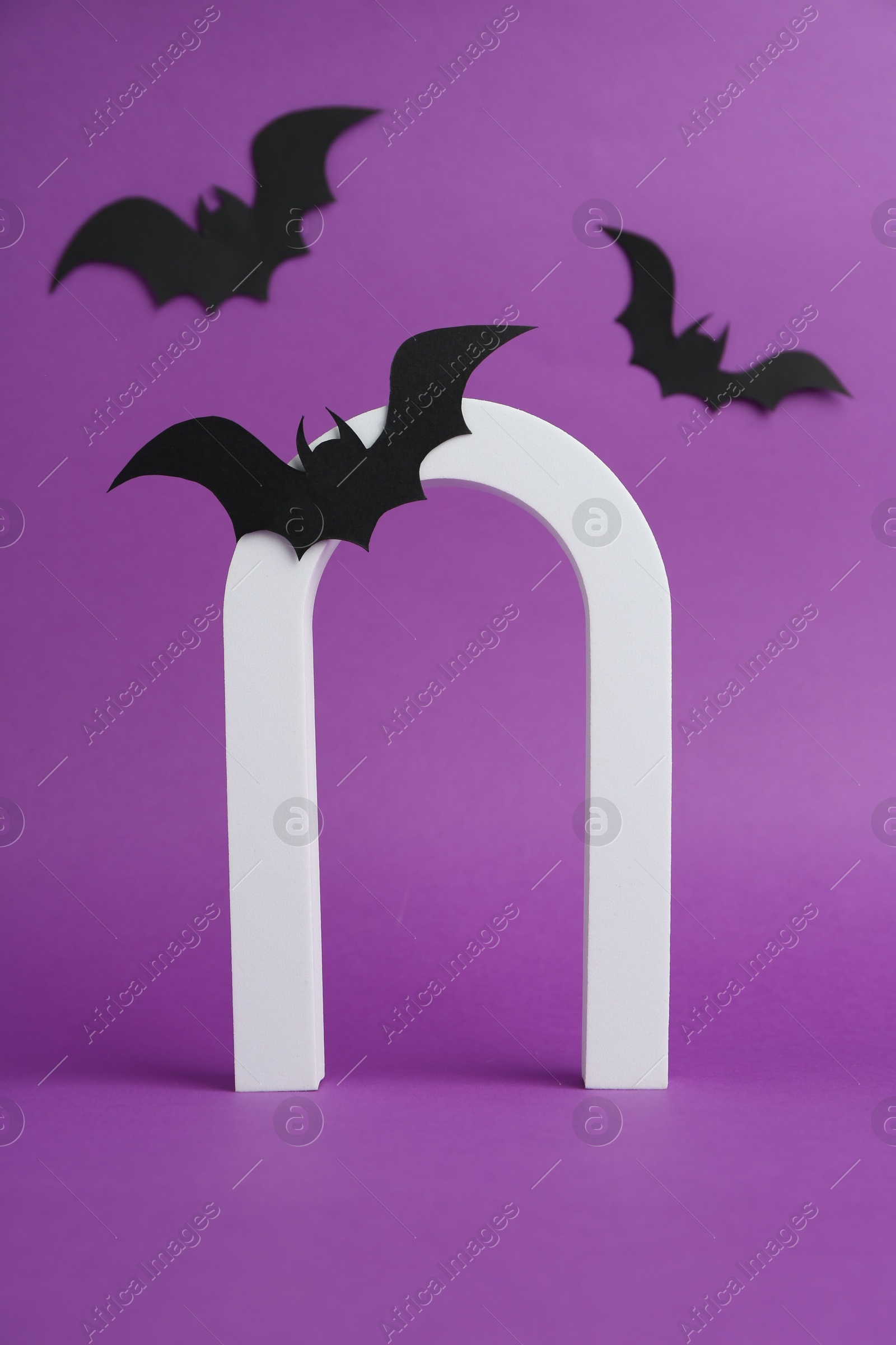 Photo of Halloween celebration. Arc and paper bats on purple background, space for text