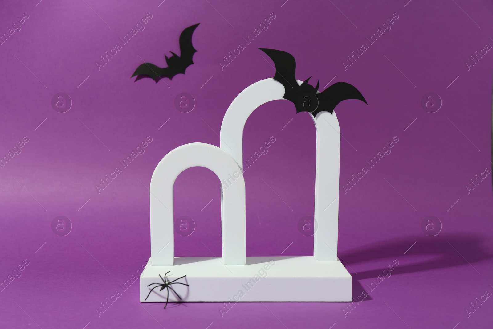 Photo of Presentation of product. Arches and Halloween decor on purple background. Space for text