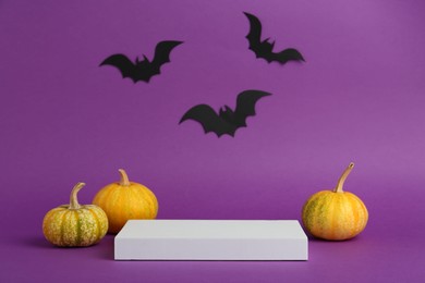 Presentation of product. Podium and Halloween decor on purple background. Space for text