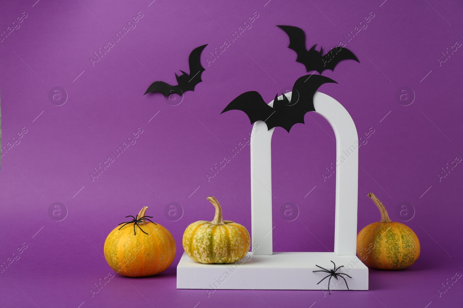 Photo of Presentation of product. Podium, arc and Halloween decor on purple background. Space for text