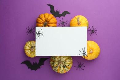 Photo of Flat lay composition with Halloween decor and blank card on purple background. Space for text