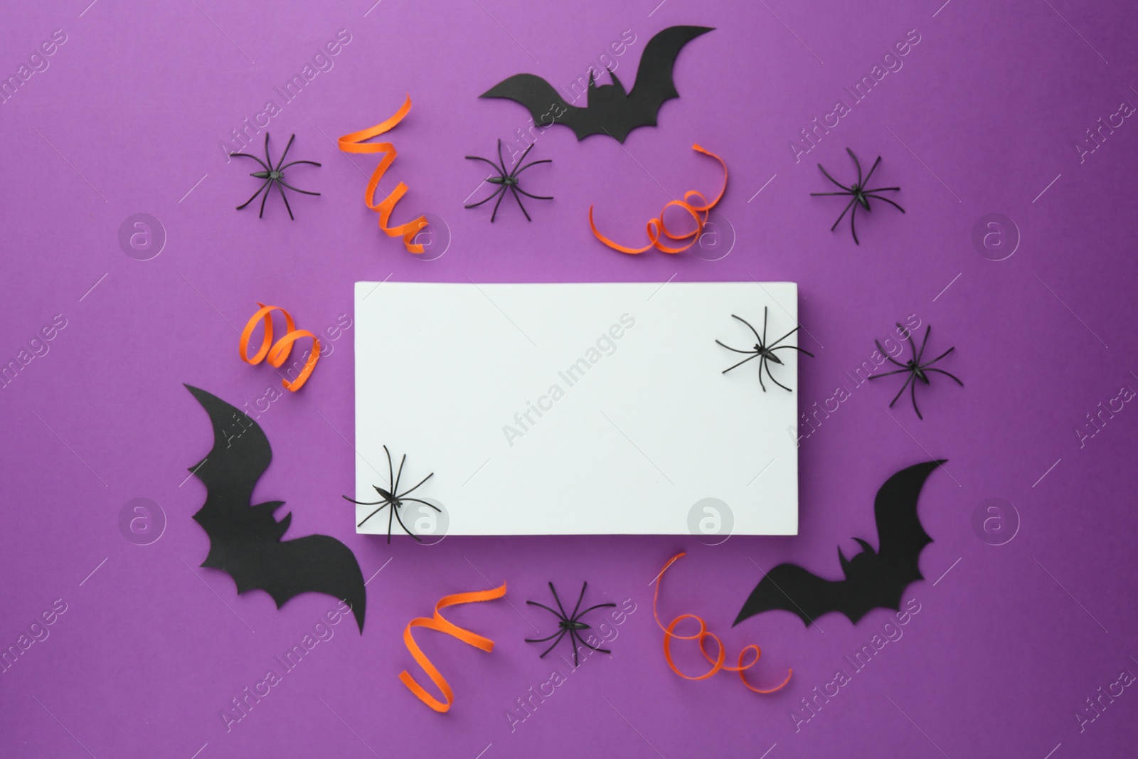 Photo of Flat lay composition with Halloween decor and blank card on purple background. Space for text