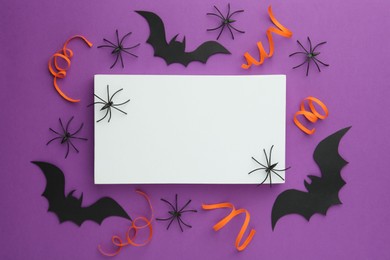 Photo of Flat lay composition with Halloween decor and blank card on purple background. Space for text