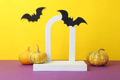 Presentation of product. Podium and Halloween decor on purple table against yellow background. Space for text