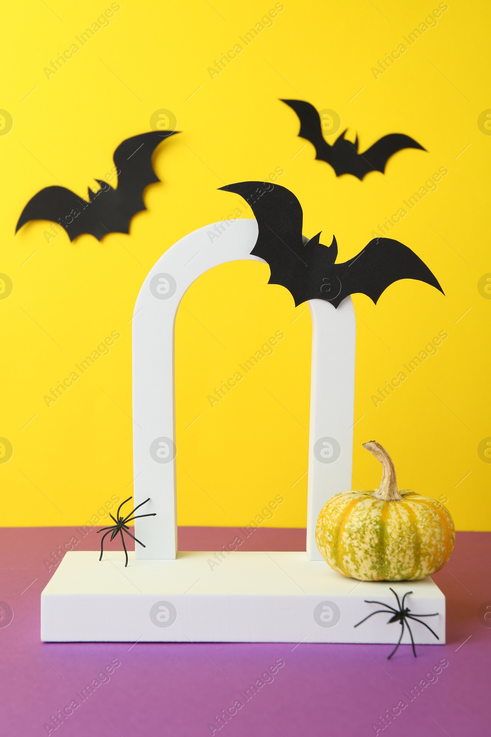 Photo of Presentation of product. Podium and Halloween decor on purple table against yellow background. Space for text