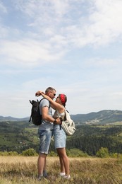 Couple with backpacks hugging outdoors. Active tourism