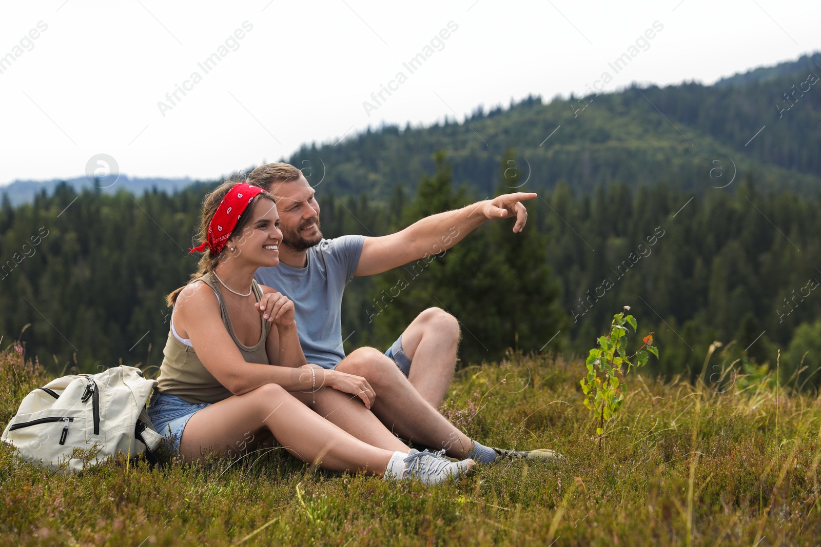 Photo of Couple with backpack looking at something outdoors, space for text. Active tourism