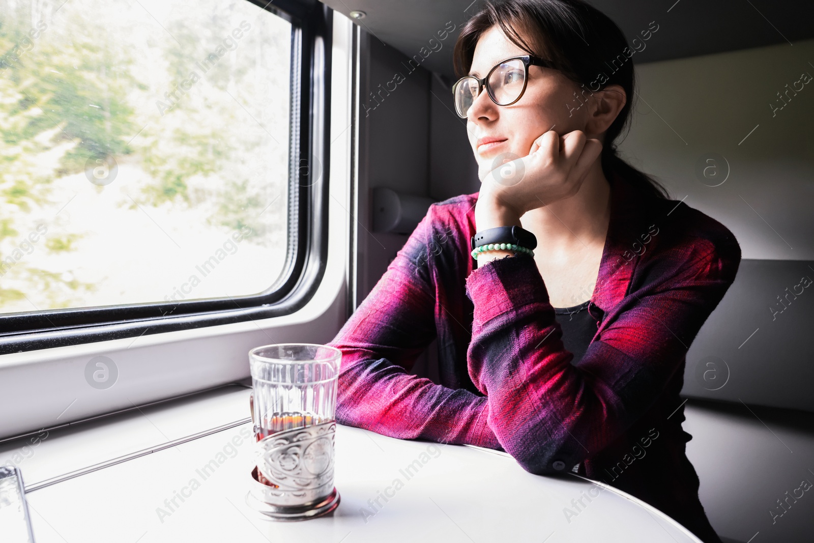 Photo of Young woman with cup of tea at table in train