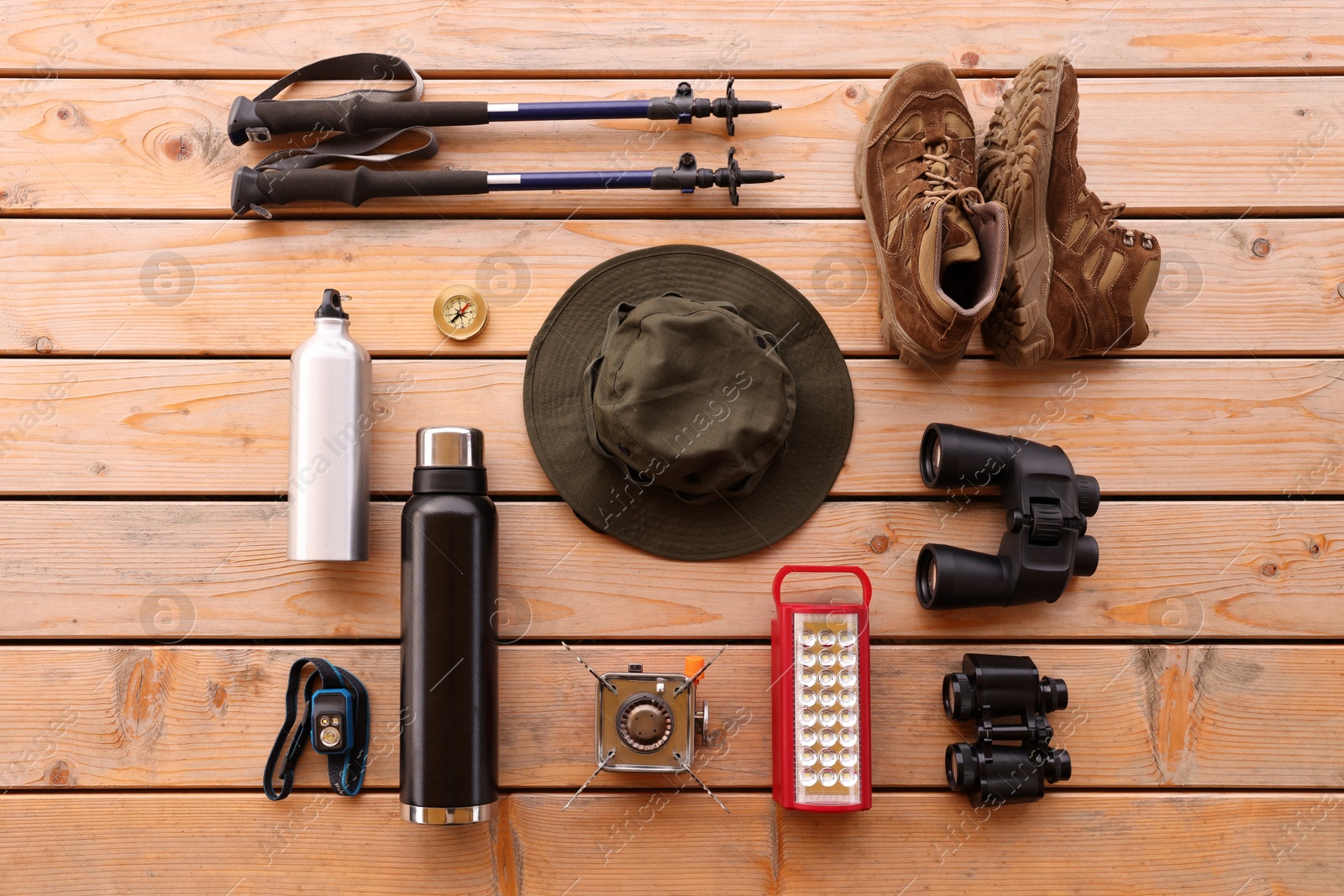 Photo of Different hiking equipment and tools at wooden table, flat lay