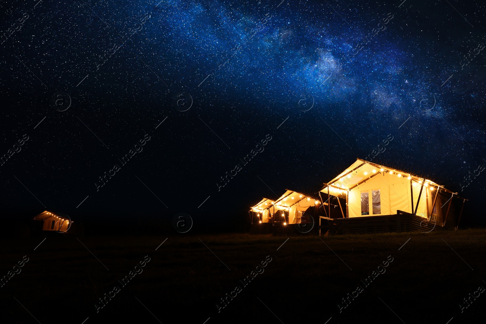 Photo of Tents in mountains at night, space for text. Glamping site