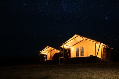 Photo of Tents in mountains at night, space for text. Glamping site