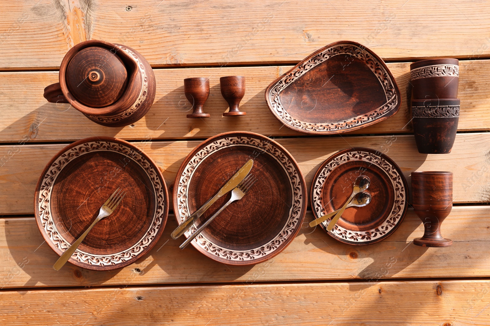 Photo of Different cutlery and tableware on wooden table, flat lay