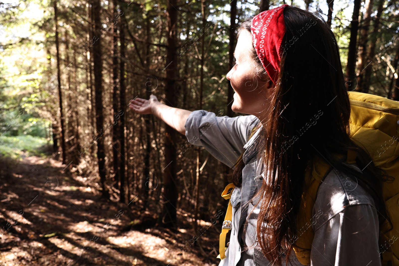 Photo of Young hiker with backpack showing something in forest