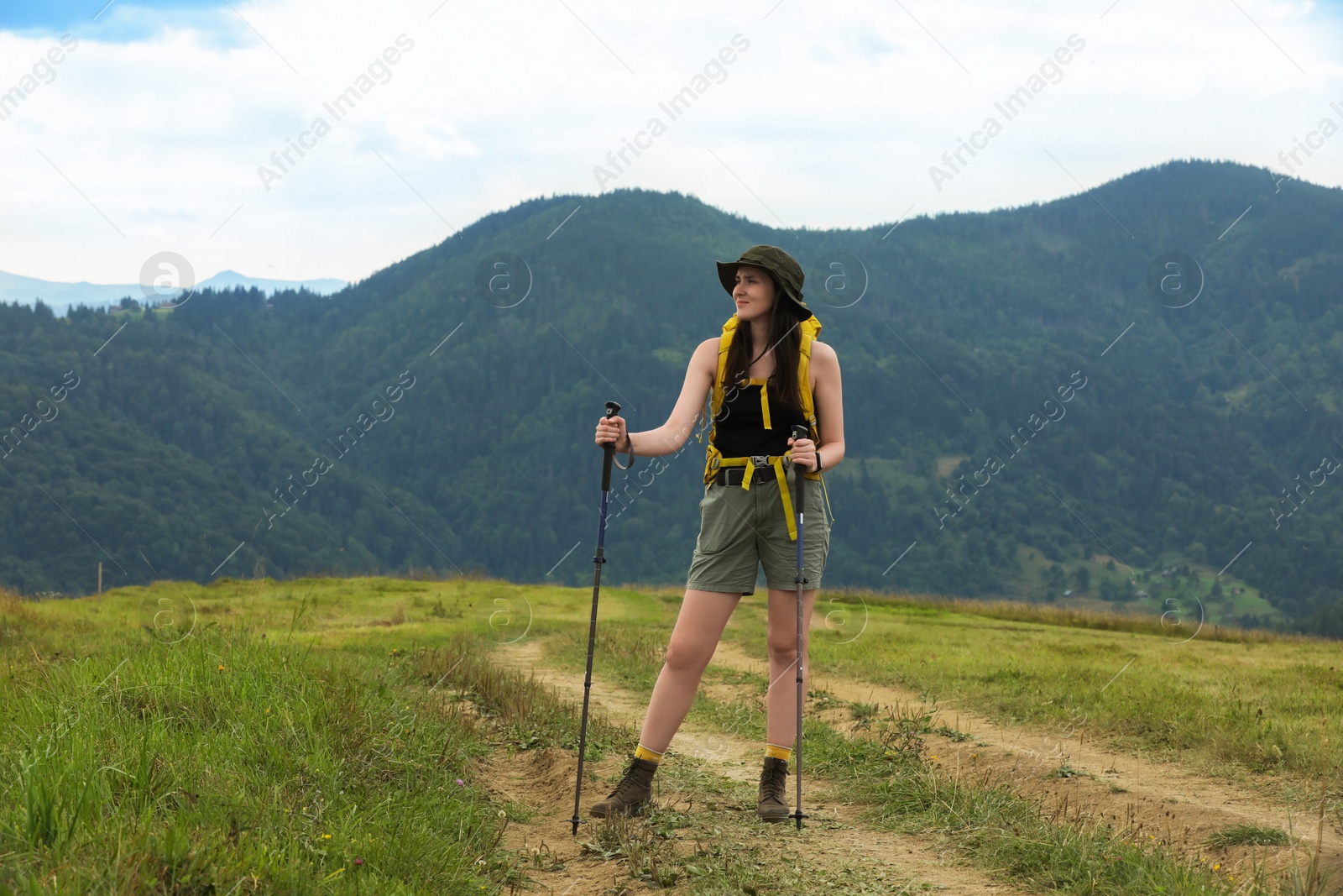 Photo of Young hiker with backpack and trekking poles in mountains