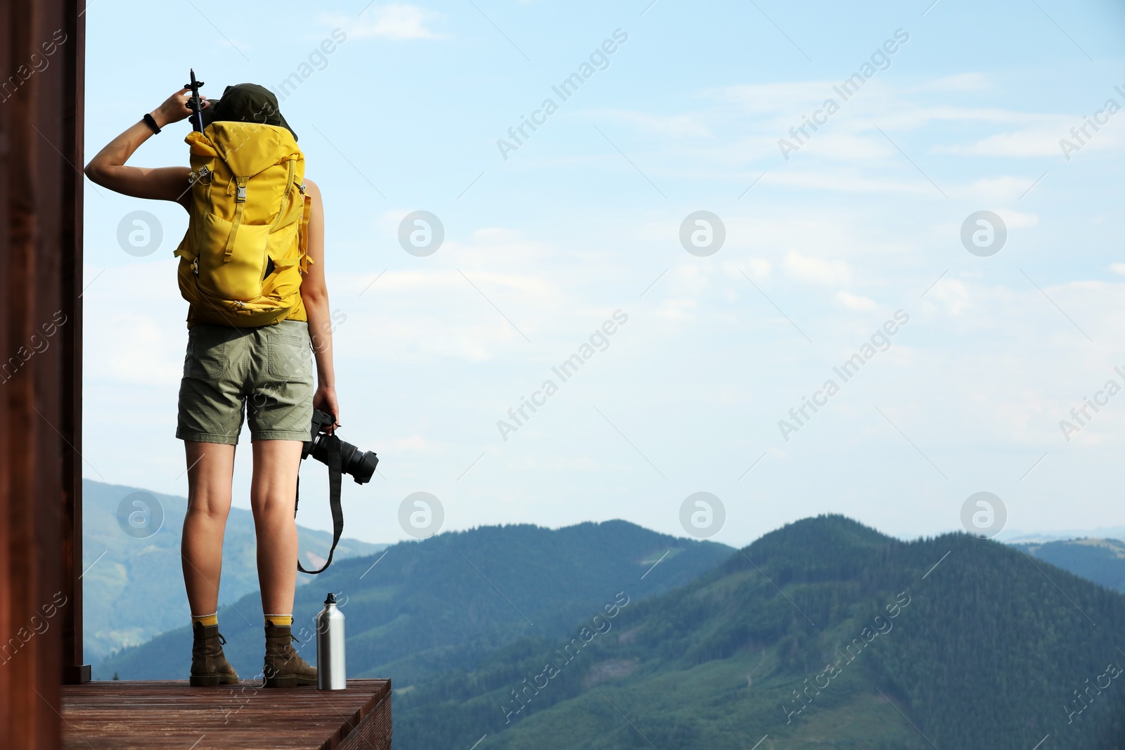 Photo of Young hiker with backpack and camera in mountains, back view. Space for text