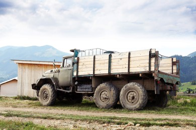 Photo of Farming equipment. Old truck in farm near mountains