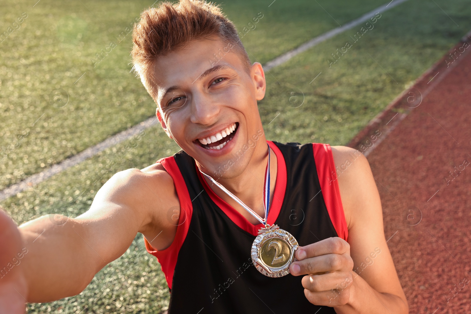 Photo of Happy winner with silver medal taking selfie at stadium