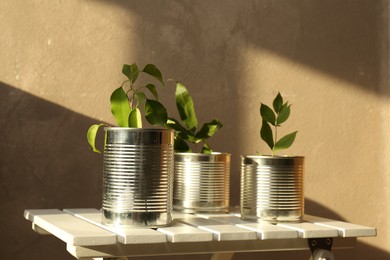 Photo of Recycling concept. Metal cans with plants on white wooden table