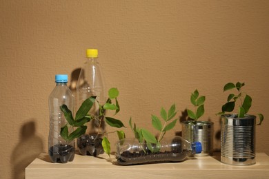 Photo of Recycling concept. Metal cans and plastic bottles with plants on wooden table