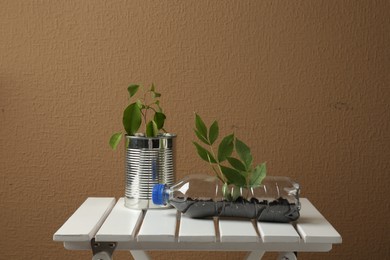 Photo of Recycling concept. Metal can and plastic bottle with plants on white wooden table