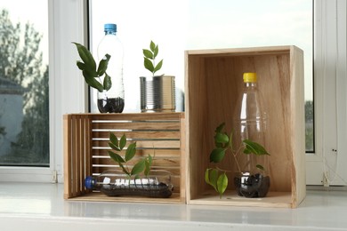 Photo of Recycling concept. Metal can, plastic bottles and wooden crates with plants on windowsill