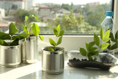 Photo of Recycling concept. Metal cans and plastic bottles with plants on windowsill