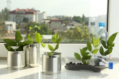 Photo of Recycling concept. Metal cans and plastic bottles with plants on windowsill