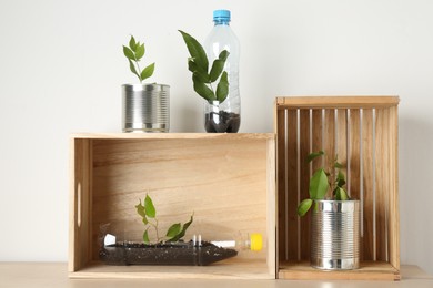 Photo of Recycling concept. Metal cans and plastic bottles with plants on wooden table