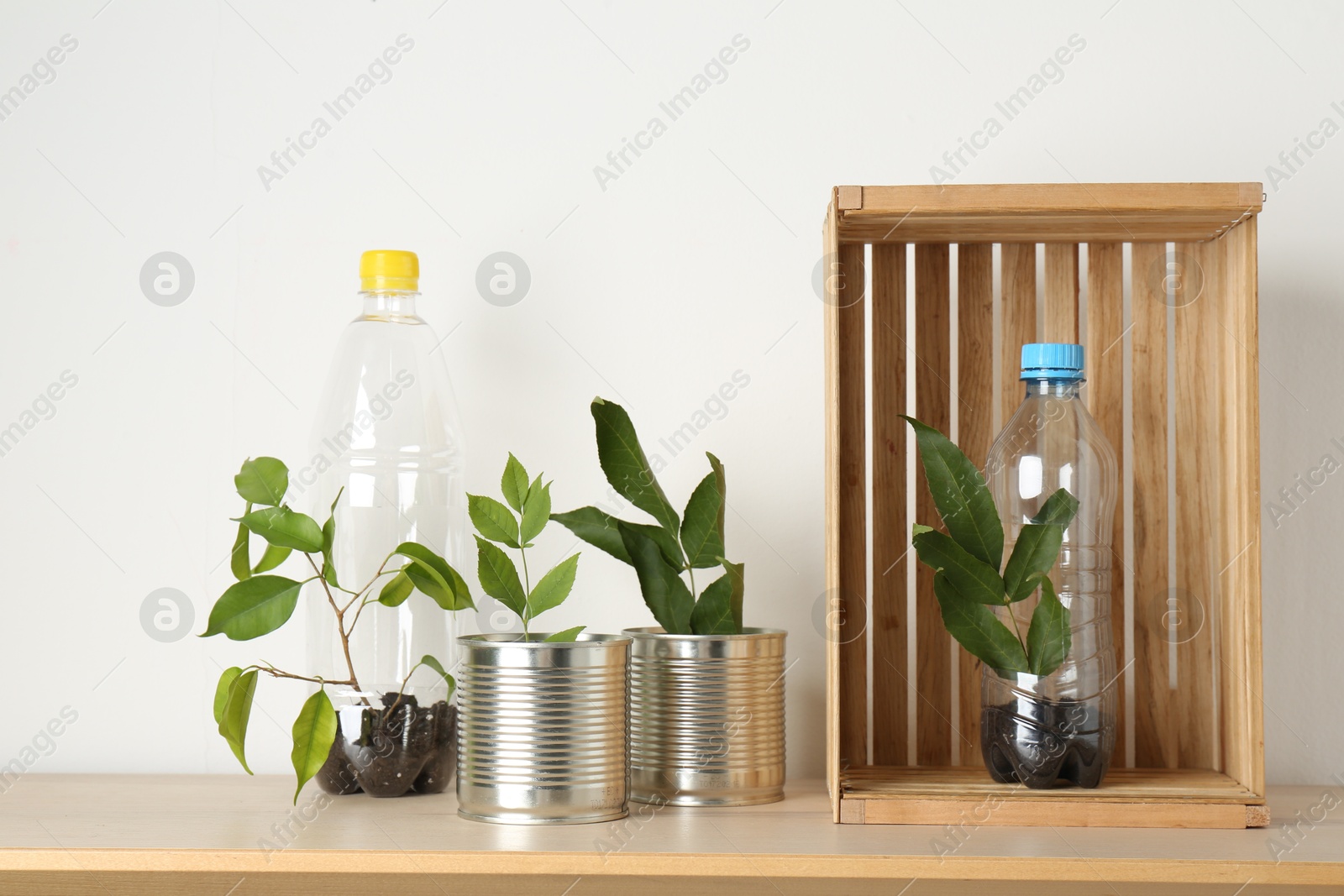 Photo of Recycling concept. Metal cans and plastic bottles with plants on wooden table